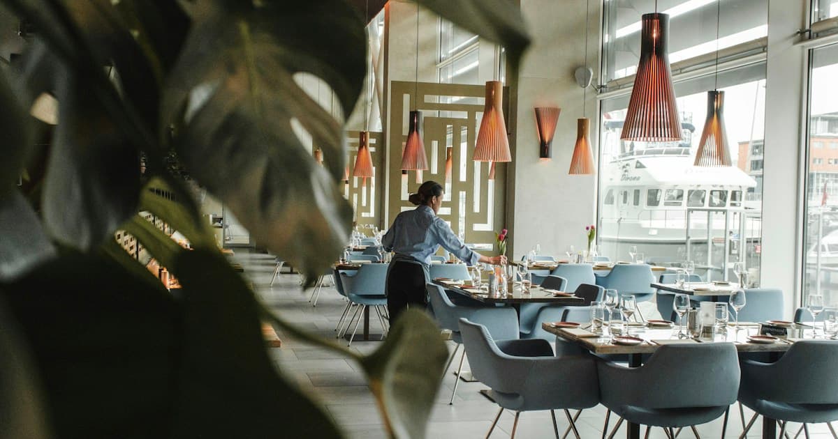 woman in front on brown dining table and chairs inside building